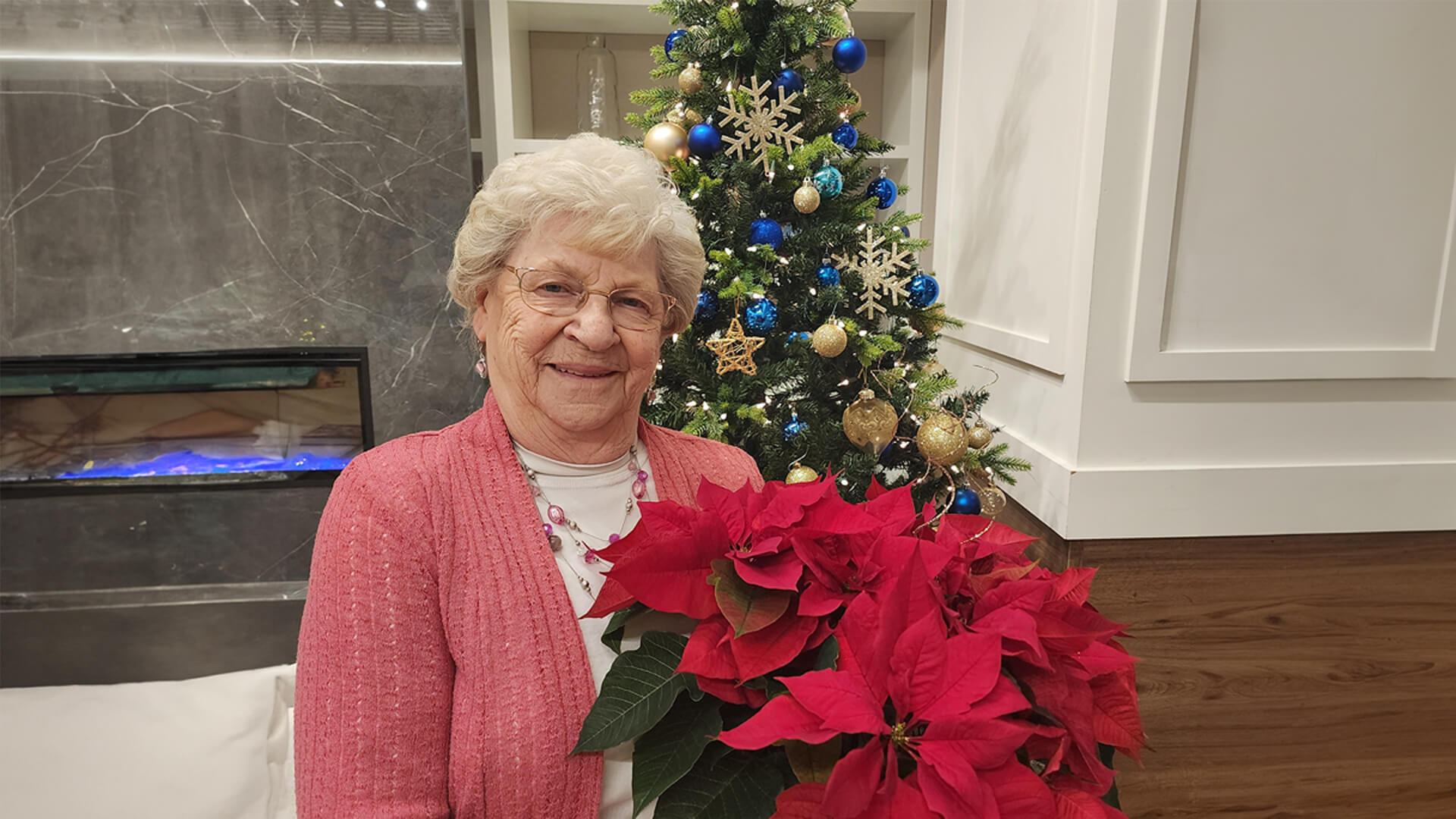 Female senior holding Poinsettia in front of a Christmas tree