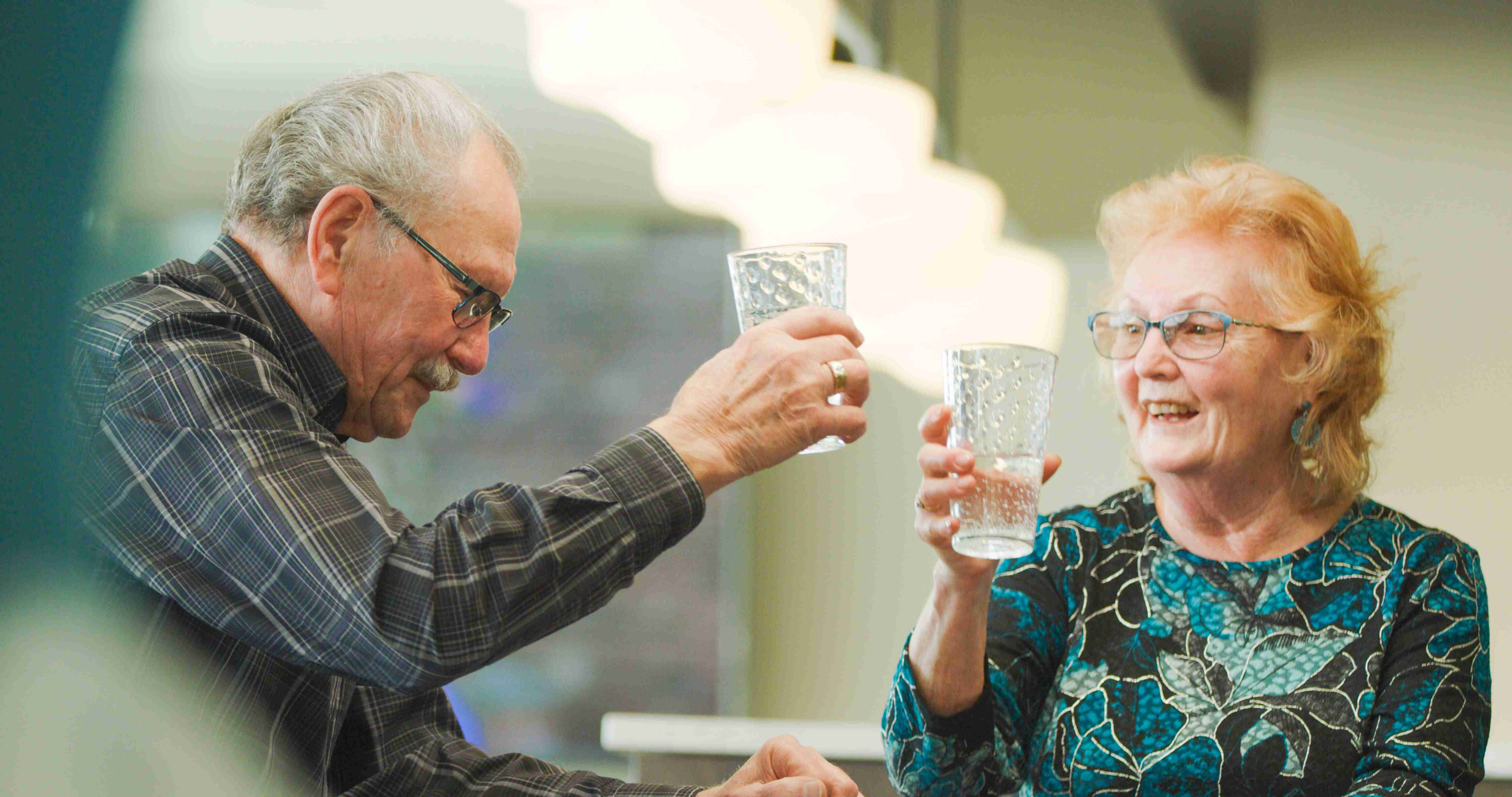 A senior couple toasting with glasses of water