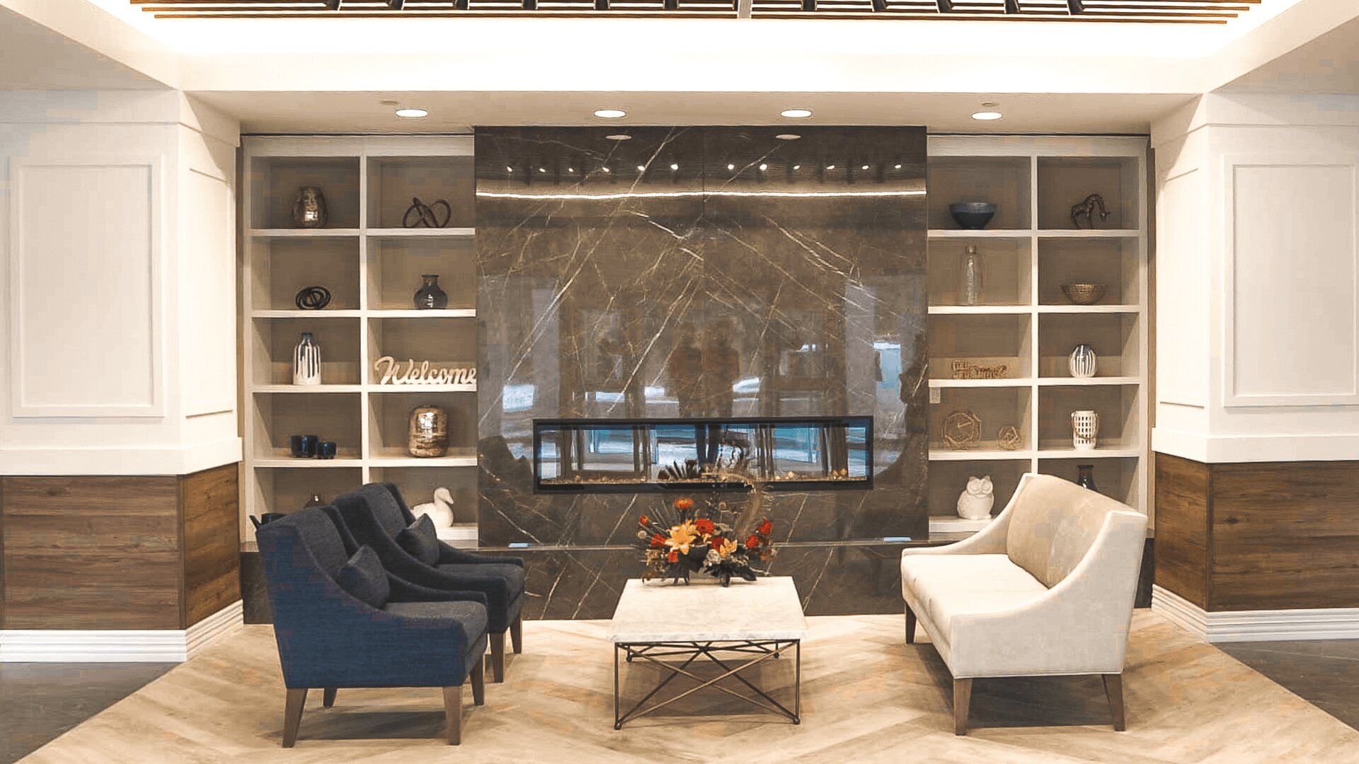 The lobby of Aster Gardens featuring a sitting area around a fireplace