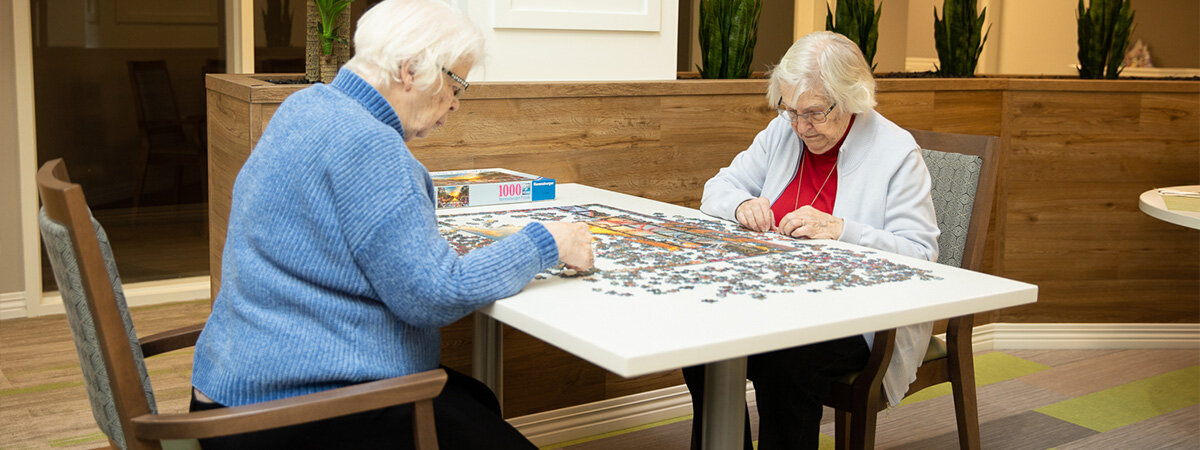 Two elderly woman solving puzzle on a table