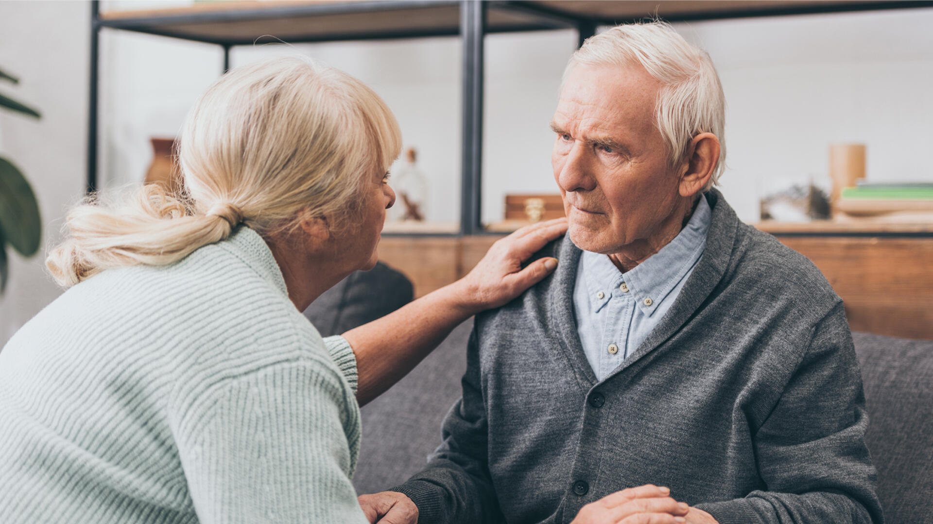 An elderly woman comforting a senior man