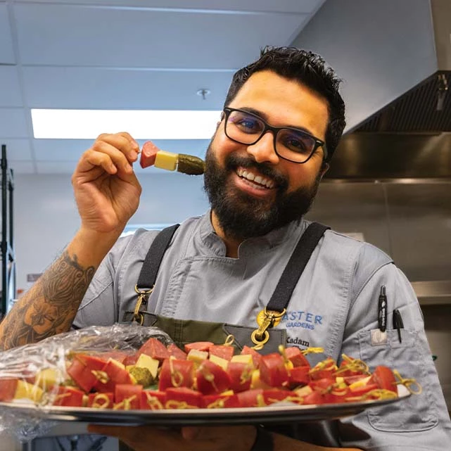 Aster Gardens chef smiling while holding some tasters prepared for the open house.