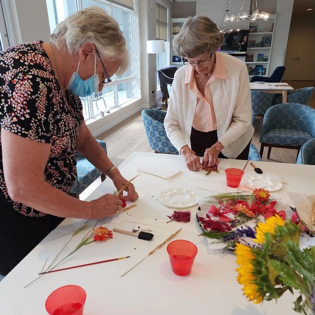 Two elderly women painting with flowers