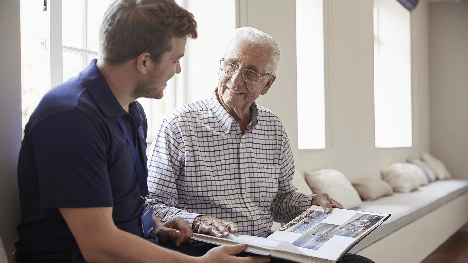 A senior man looking through a book with a young man