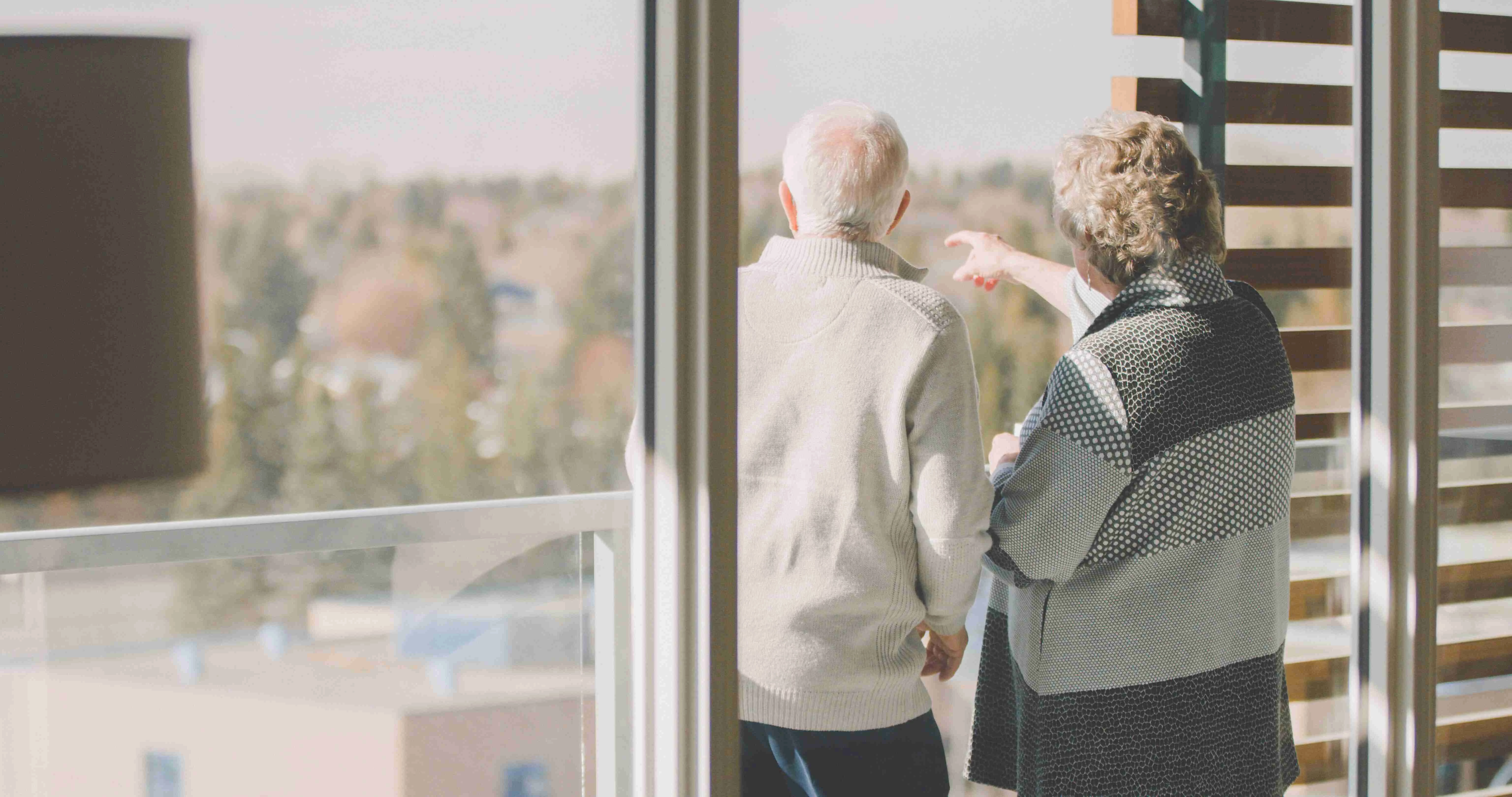 An elderly couple enjoying the view while standing at the balcony