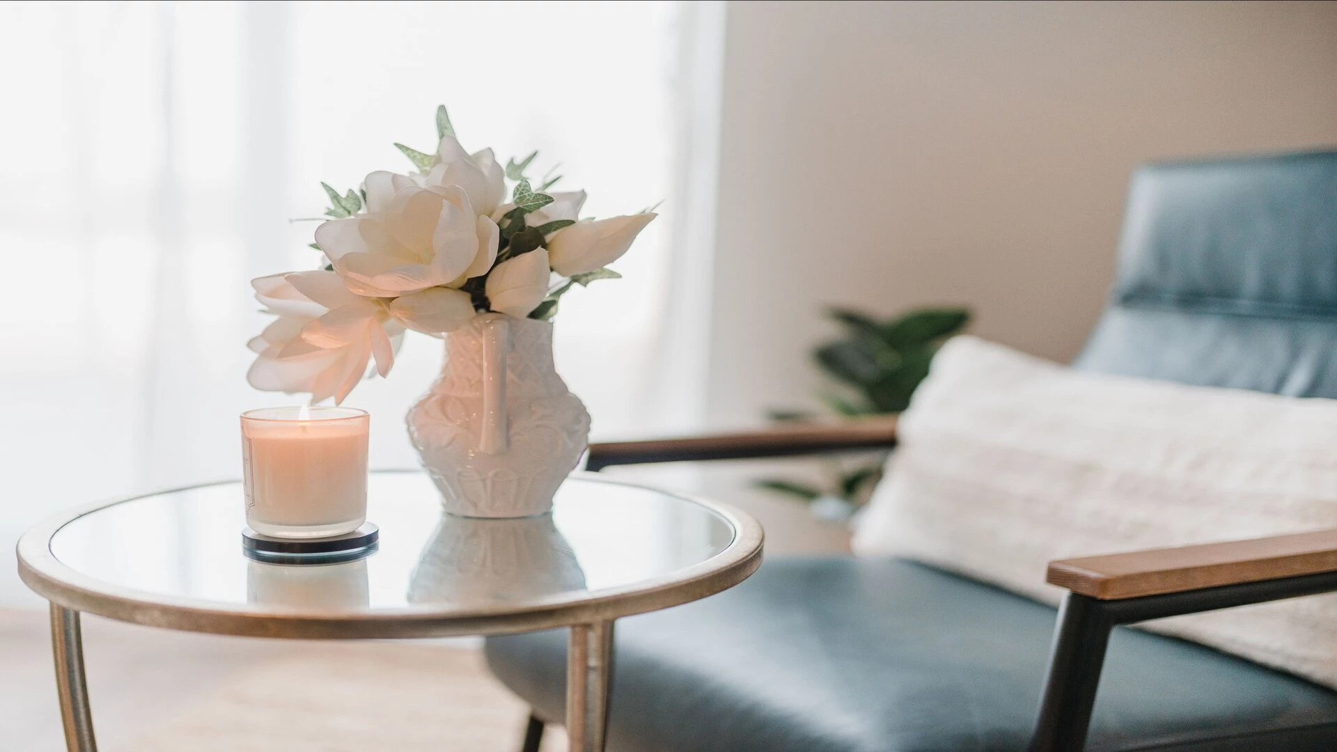 A table with a candle and white flowers in a white vase