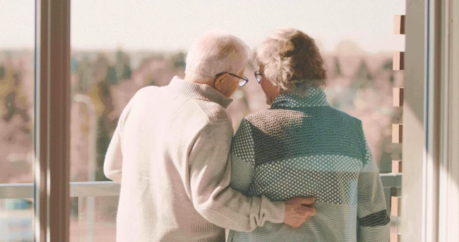 A senior couple hugging and looking over a balcony