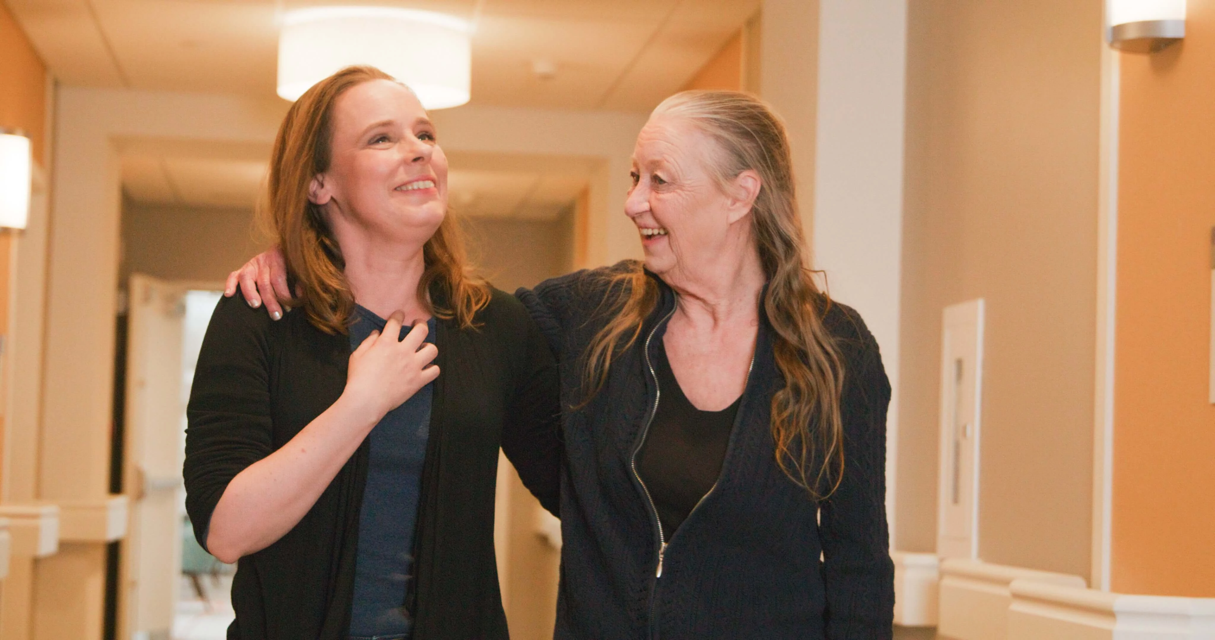 A senior woman with her arm around a younger woman