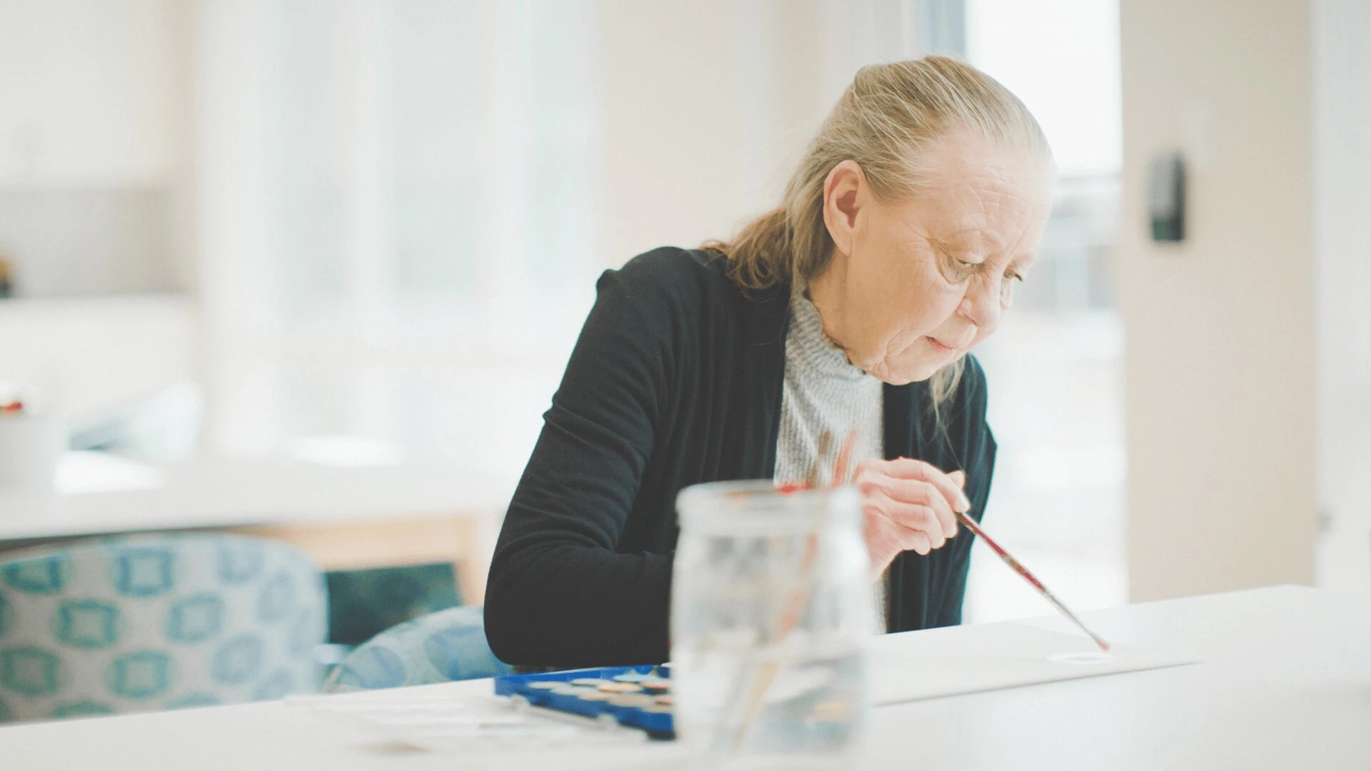 A senior woman painting on a canvas