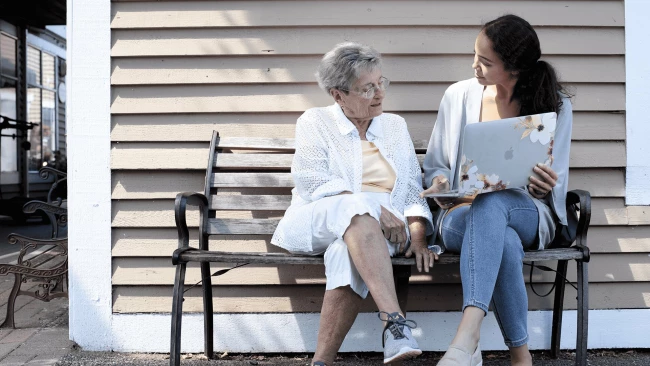 A young woman showing a senior woman a laptop computer