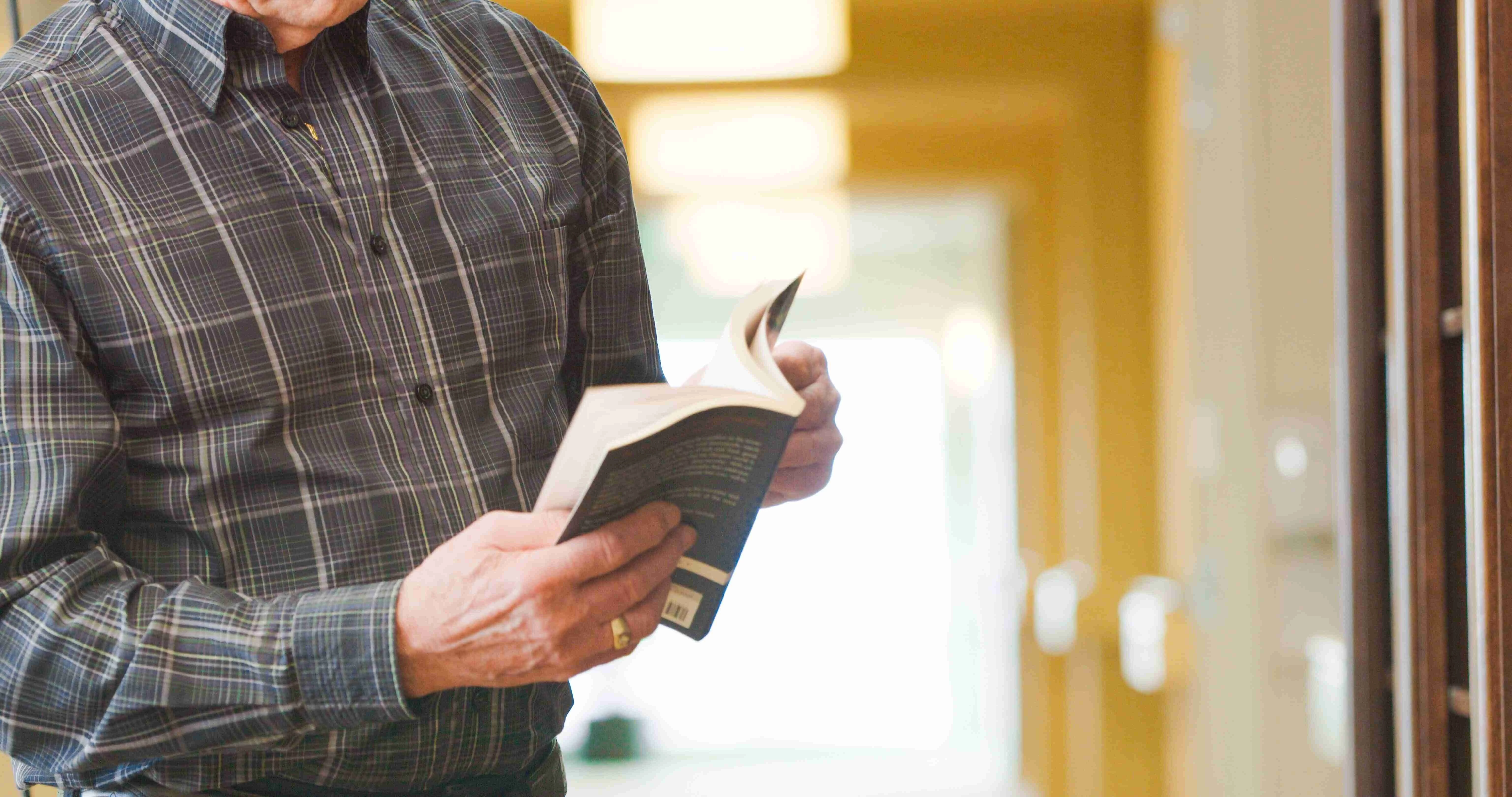 A senior citizen reading a book at Aster Garden's Library